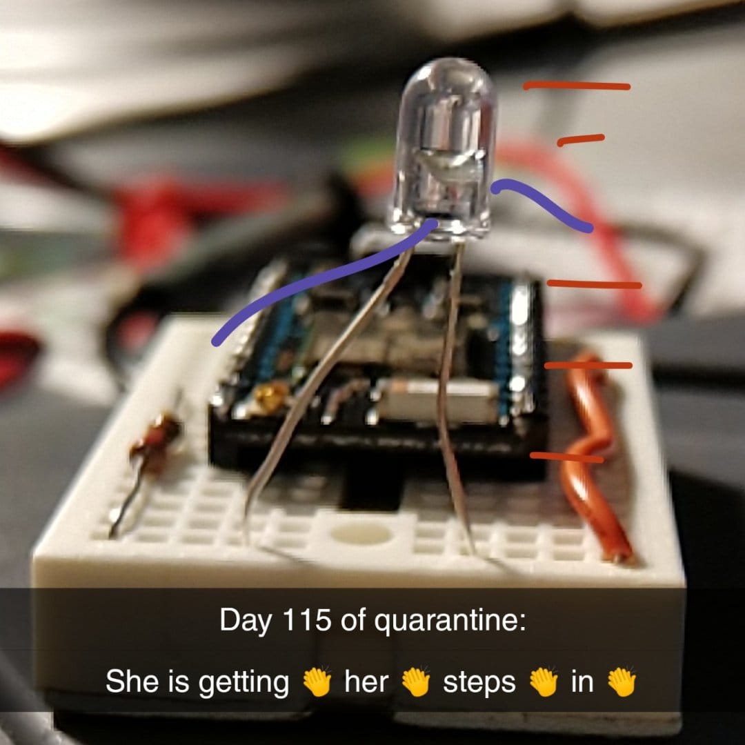 A picture of an IR diode stuck into a breadboard positioned in a way that it looks like it is walking, with arms drawn on, captioned: "Day 115 of quarantine: She is getting 👏 her 👏 steps 👏 in 👏"